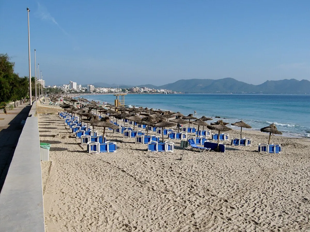 Sandstranden i Cala Millor med parasoller og fjellene i bakgrunnen